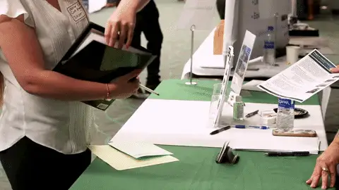 Person nimmt Unterlagen an einem Messetisch entgegen